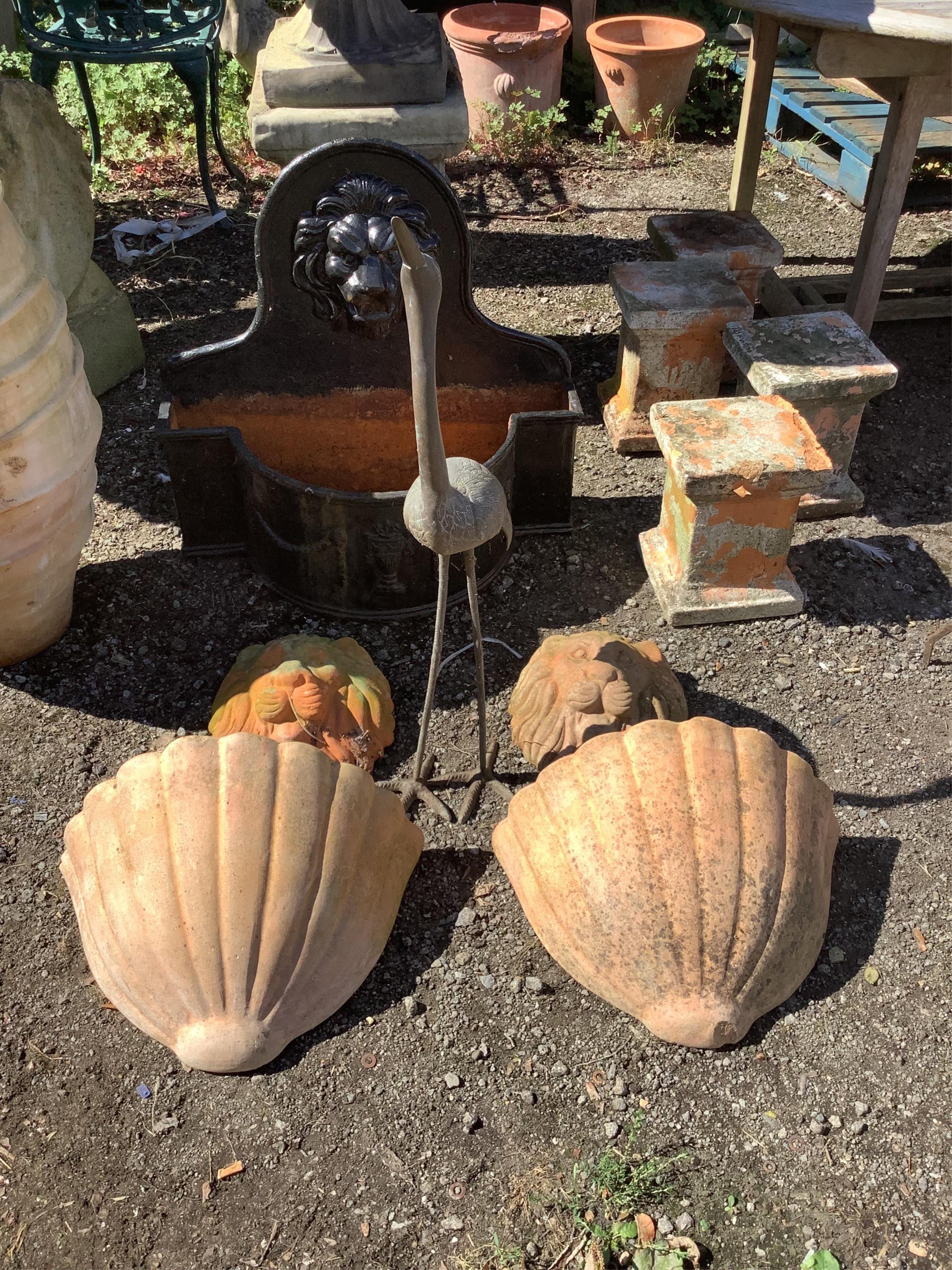 A bronzed metal stork garden ornament, a pair of terracotta lion mask wall appliqués and a pair of terracotta wall garden planters, a pair of blue glazed fountain balls and a set of three blue glazed square planters, 38c